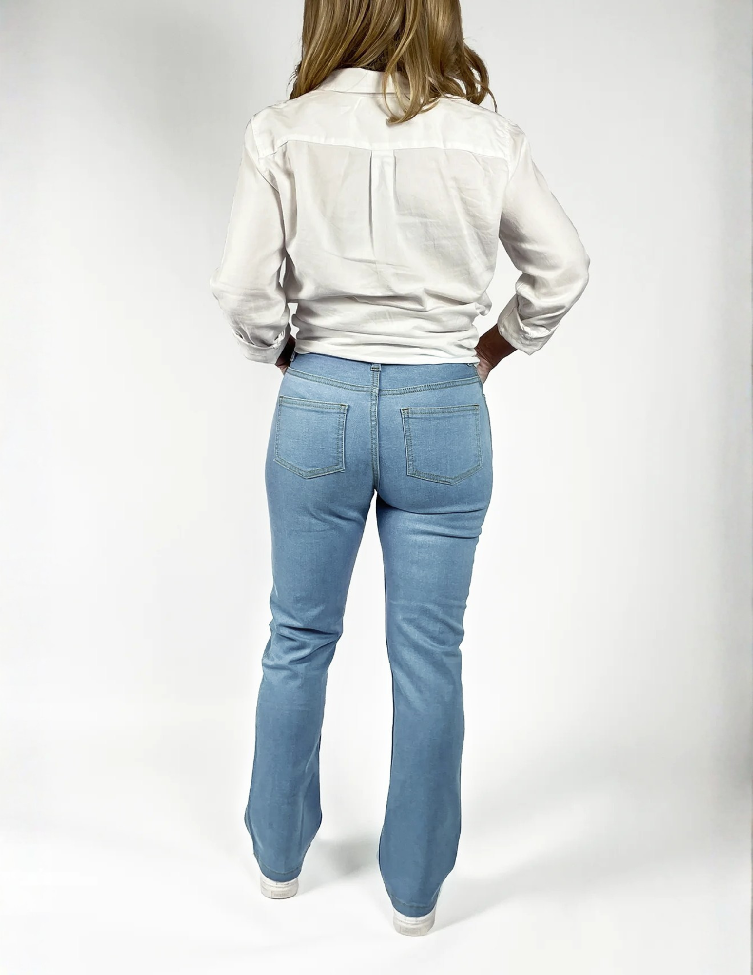 Woman wearing Say Yes to the Jeans style pants with a white shirt on a white background