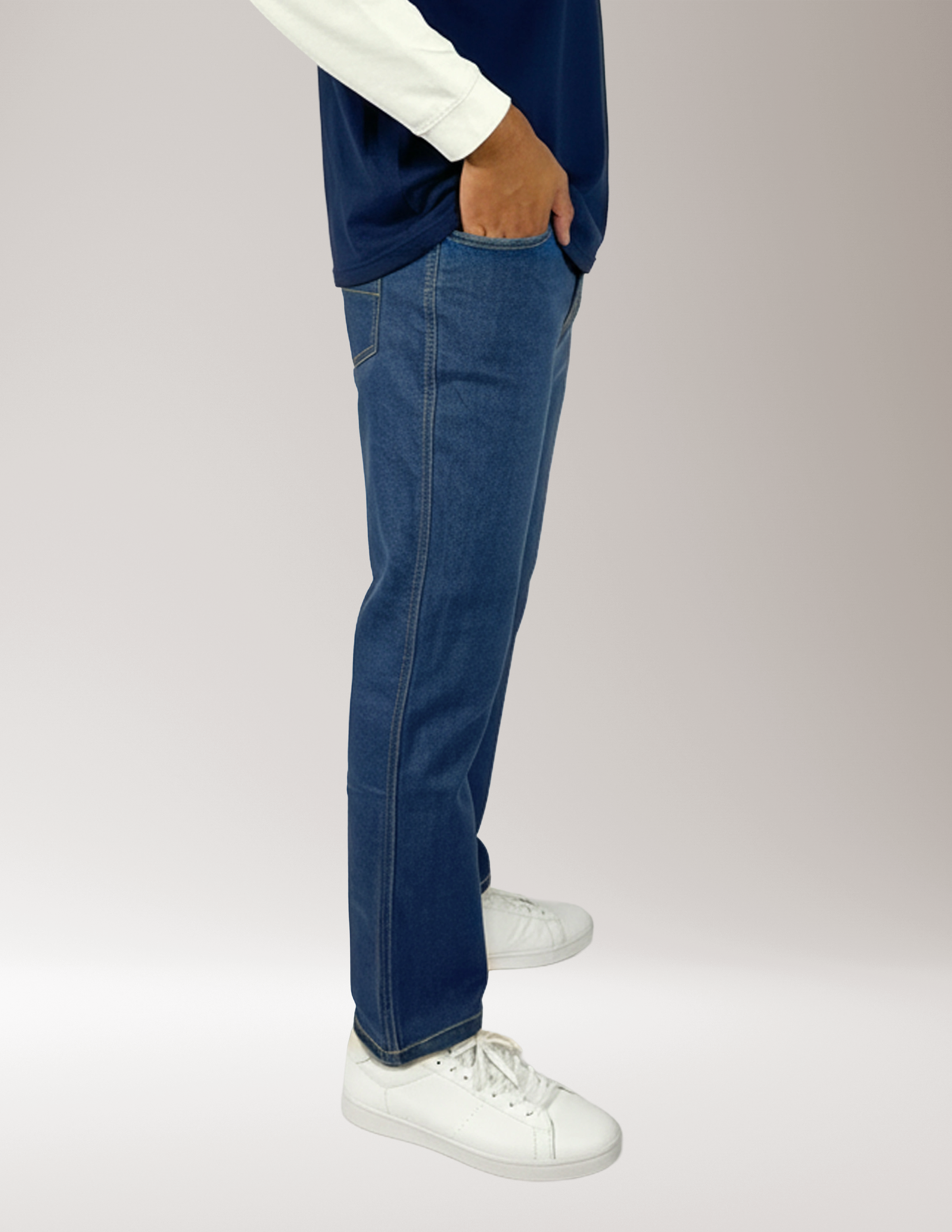 Man wearing Jeanius Denim style pants and white sneakers on a plain background