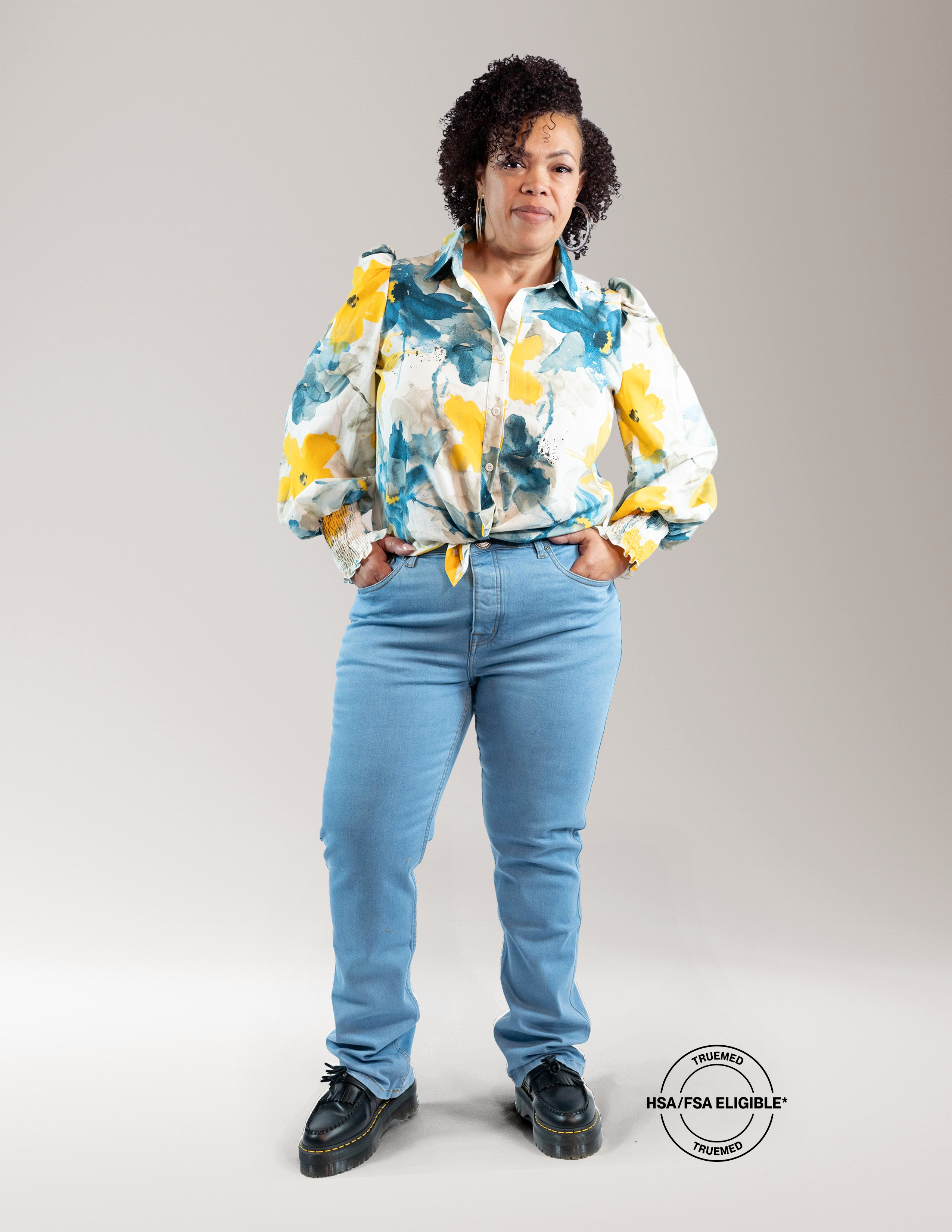 African American woman wearing Say Yes To The Jeans that is a light colored denim. Wearing multi color button down shirt with black shoes