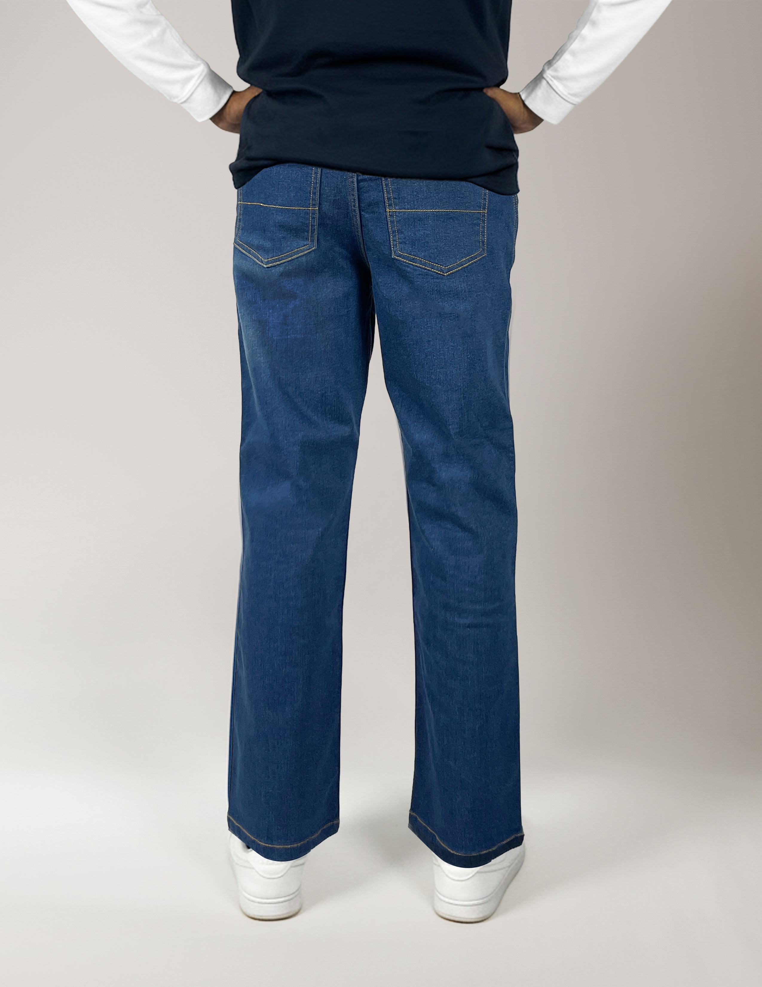 Man wearing Jeanius Denim style pants and a dark shirt on a plain background